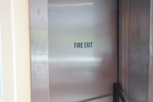 A visible fire exit sign stands out in a busy city near a vibrant yellow taxi cab