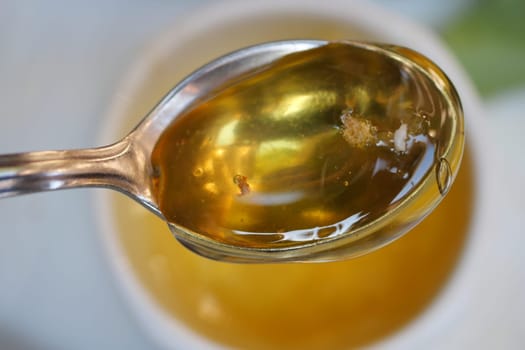 A delicious golden honey is elegantly pouring into a beautifully vibrant blue bowl