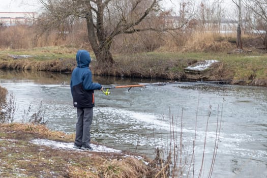 Shot of the boy fishing on the winter river