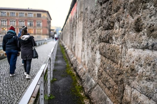 Berlin, Germany - 21 December 2022: Tourists walking near Broken Berlin wall between East and west Berlin, symbol of the Cold War