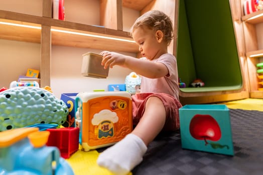Toddler playing with educational blocks in colorful indoor playroom for kids
