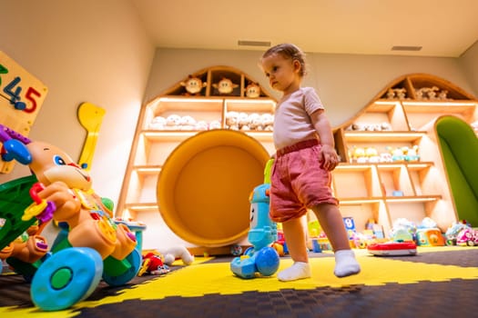 Toddler playing with a toy vacuum cleaner in a colorful playroom for learning and development