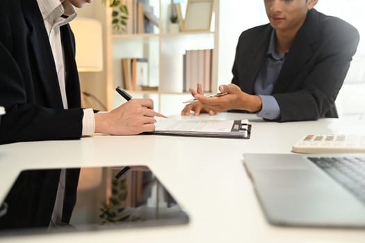 Cropped shot of professional advisor and client reviewing and discussing contract terms in a bright office.