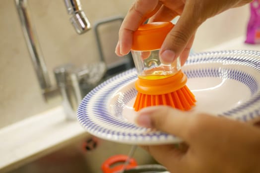A person is scrubbing a bowl in a kitchen, ensuring cleanliness and hygiene standards