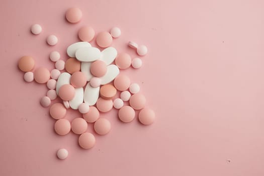 A vivid mix of pink and white pills scattered on a soft pink surface, creating eyecatching art