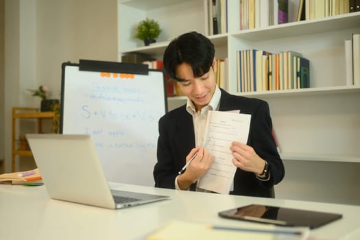 Smiling tutor explaining a worksheet to student during an online learning session.