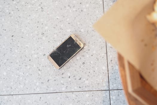 Top view of broken smart phone on tiles floor .
