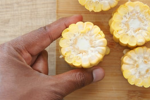 Fresh corn slices on a wooden cutting board with a yellow-handled knife, perfect for meal prep.
