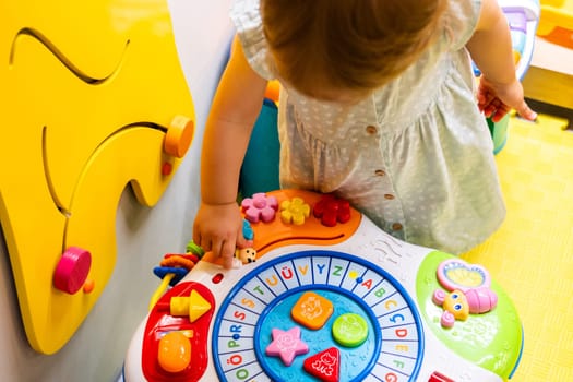 Toddler enthusiastically engaging with an educational toy in a vibrant playroom. Concept of joyful learning and promoting fine motor skill development in a fun environment