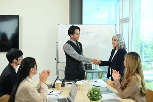 Shot of business partnership shaking hands after reaching a successful agreement during meeting.