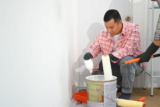 Two men decorating room in new home painting wall together.