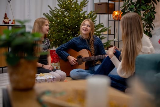 Three close friends are having a warm and cozy, musical evening filled with joy during the festive holiday season