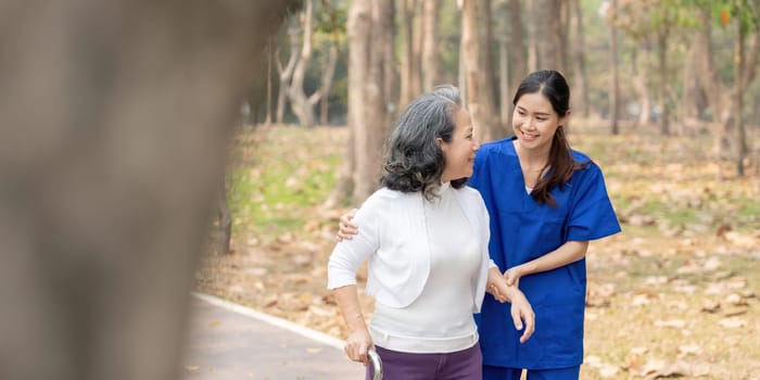 Nurse and senior in elderly care, support or walking with stick at park. Medical caregiver or therapist help patient or person with a disability in retirement or physiotherapy.