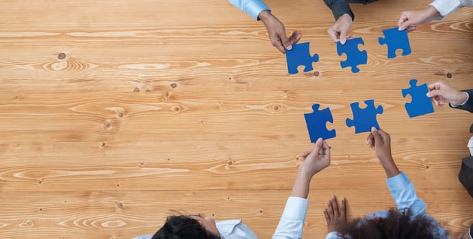 Panorama top view diverse corporate officer worker collaborate in office connect puzzle piece as partnership and teamwork concept. Unity and synergy in business success with jigsaw puzzle. Concord