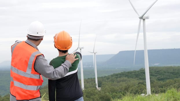 Engineer with his son on a wind farm atop a hill or mountain in the rural. Progressive ideal for the future production of renewable, sustainable energy. Energy generation from wind turbine.