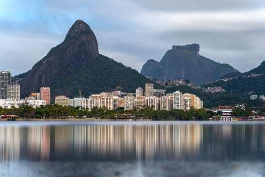 Long exposure shot of Rio de Janeiro's Lagoa with residential buildings, Rosinha favela, and Two Brothers and Pedra da Gavea rocks.