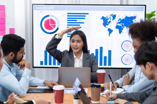 Young asian businesswoman presenting data analysis dashboard on TV screen in modern meeting. Business presentation with group of business people in conference room. Concord