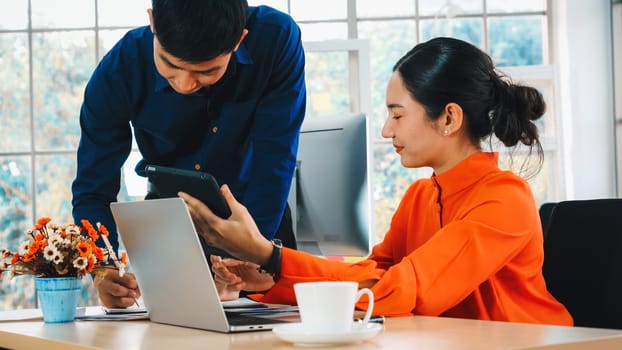 Two business people talk project strategy at office meeting room. Businessman discuss project planning with colleague at modern workplace while having conversation and advice on financial report. Jivy