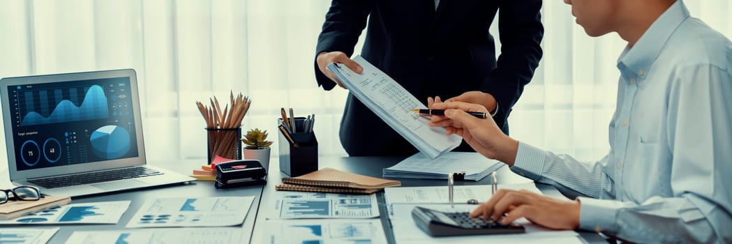 Auditor team collaborate in office, analyzing financial BI data dashboard on laptop screen and accounting record. Finance and taxation with accurate report and planning for company budget. Insight