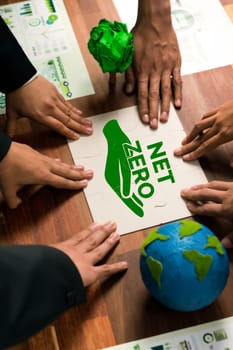 Cohesive group of business people forming jigsaw puzzle pieces in net zero icon symbol as eco corporate responsibility to reduce CO2 emission as sustainable solution for greener Earth. Quaint