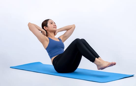 Asian woman in sportswear doing crunch on exercising mat as workout training routine. Attractive girl in pursuit of healthy lifestyle and fit body physique. Studio shot isolated background. Vigorous