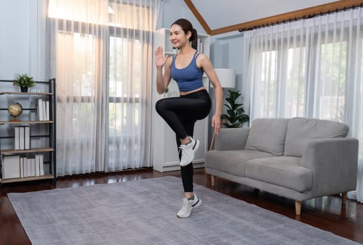 Energetic and strong athletic asian woman running in place at her home. Pursuit of fit physique and commitment to healthy lifestyle with home workout and training. Vigorous