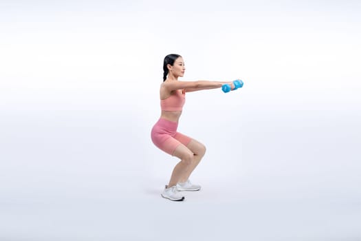 Vigorous energetic woman doing dumbbell weight lifting exercise on isolated background. Young athletic asian woman strength and endurance training session as body workout routine.