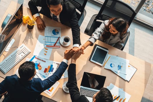 Happy business people celebrate teamwork success together with joy at office table shot from top view . Young businessman and businesswoman workers express cheerful victory show unity support . Jivy