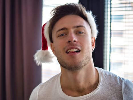 A man wearing a santa hat making a funny face. Photo of a man wearing a Santa Claus hat making a funny expression