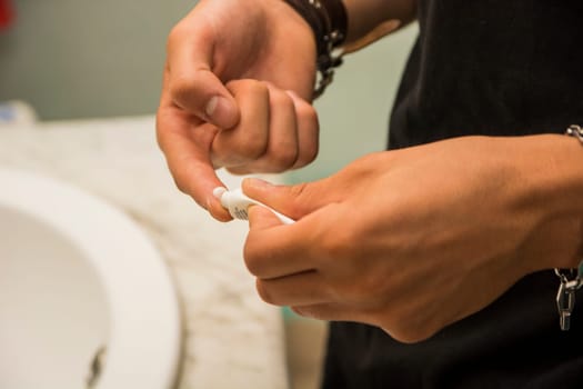 Close up of hands of a man squeezing a moisturizing cream tube onto his finger