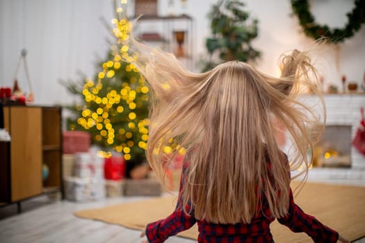 A joyful child revels in the holiday spirit with hair blowing freely among vibrant Christmas lights and decor