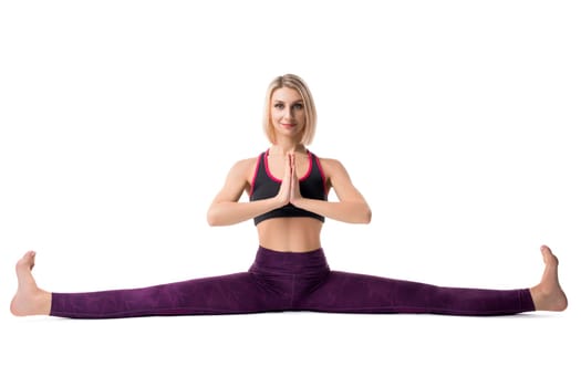 Slim blonde in sportswear sitting in a split on the floor isolated view