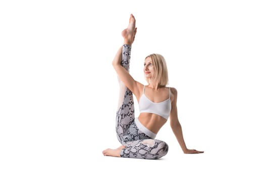 Young attractive woman with blonde hair stretching leg and looking away isolated on white background
