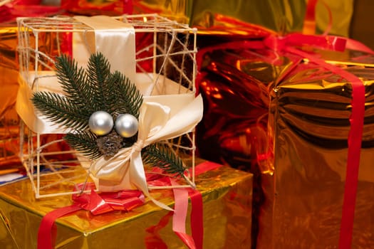 Colorful gifts wrapped in shiny paper create a festive atmosphere. One gift features a ribbon and evergreen accents, adding a charming touch to the display.