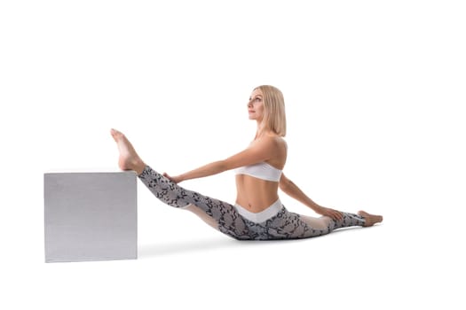 Attractive woman with blonde hair stretching legs and looking away isolated on white background
