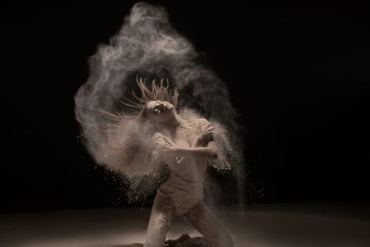 Woman on her knees in white dust cloud shot in the dark room