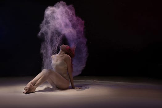 Brunette on the floor in violet dust cloud shot in the dark room