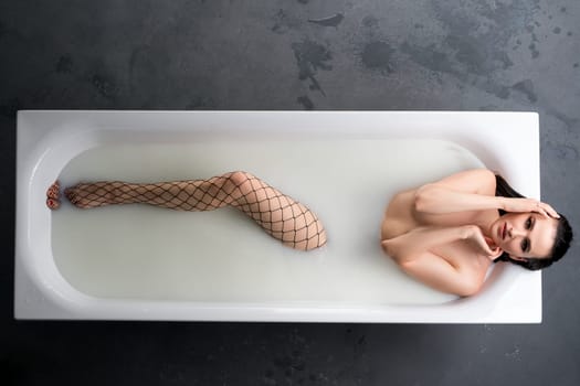 Ypung girl wearing stockings having bath in foam high angle full-length view