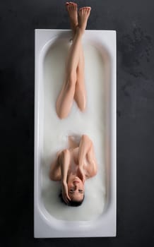 Gorgeous woman in the nude having bath in foam high angle full-length view