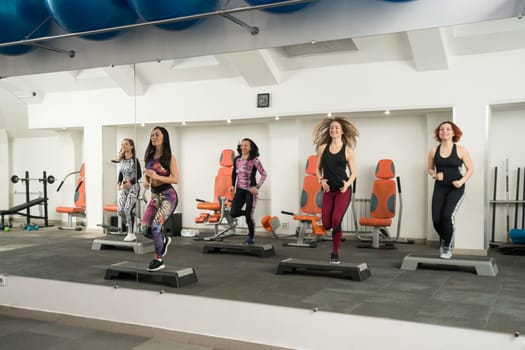 Group of girls in sportswear in a gym exercising on step platforms shot