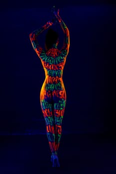 Girl with colorful UV bodyart full-length rearview against blue background