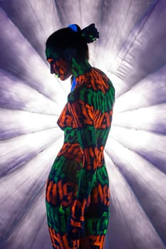 Girl with colorful UV bodyart rearview against blue background