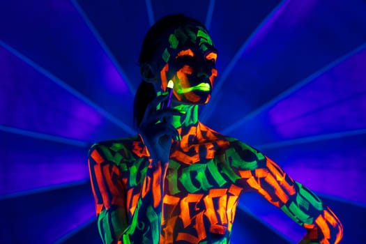 Girl with colorful UV bodyart waisteup shot against blue background