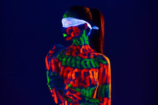 Girl with beautiful UV bodyart with white ribbon on her eyes cropped shot against dark blue background