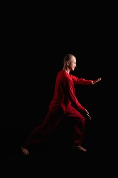 Man wearing red costume doing exercises profile shot in the dark room
