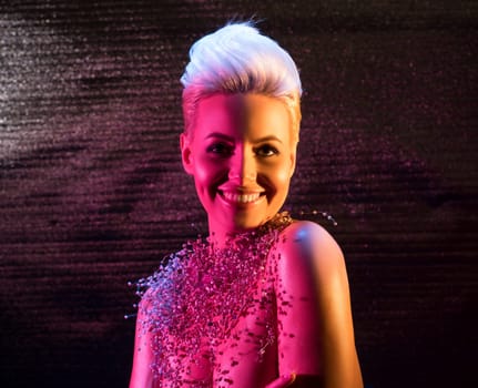 Gorgeous woman topless wearing only bijouterie waist up portrait in pink light