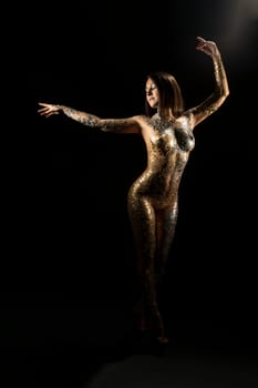 Nude brunette with gold bodyart shot in the dark room