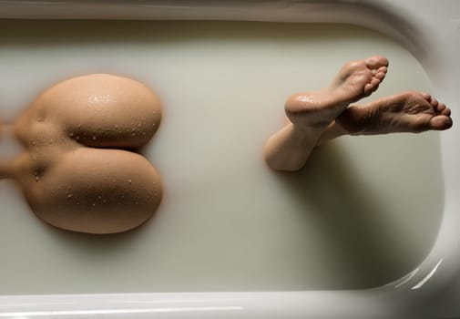 Nude woman lying in bath high angle croppped rearview
