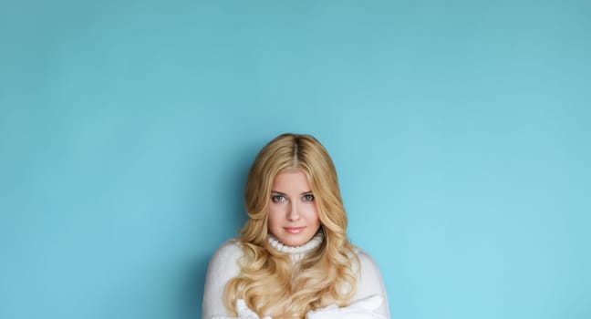Winter portrait on blue background, happy blonde woman wearing warm mittens and knitted jumper, fashion and lifestyle idea
