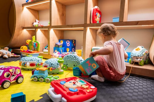 A curious toddler playing with various educational toys in a colorful and lively playroom. Concept of creativity and learning through play